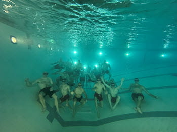 Group of people holding their breath sitting on the bottom of a pool