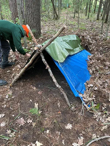 person builds makeshift shelter in the woods