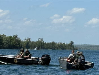 people sitting on two boats on a lake