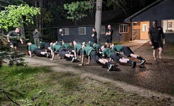 people doing pushups outside of a cabin in the dark