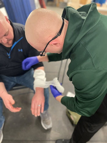 man wrapping gauze on a person's arm