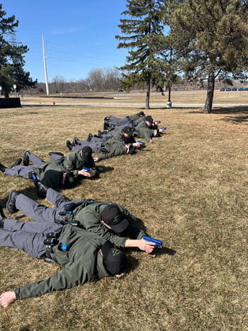 people laying on ground outside using training firearms