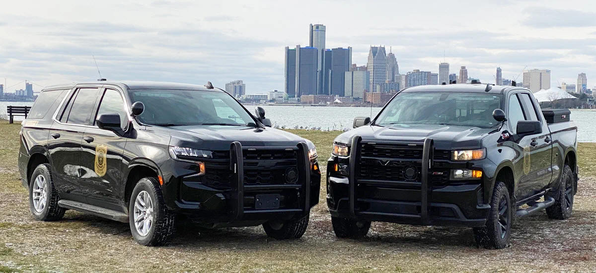 Two patrol trucks with Detroit skyline