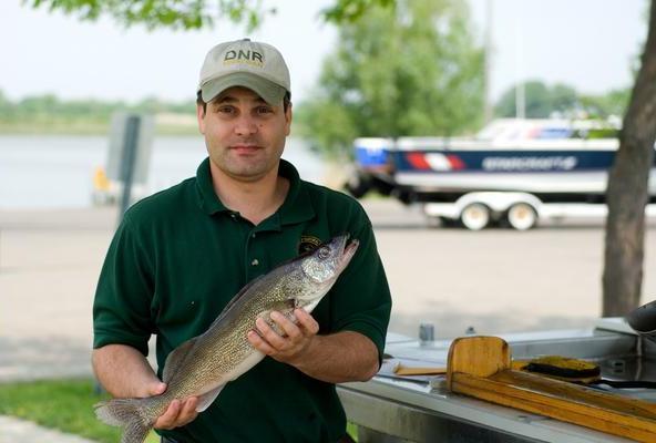 Creel clerk holds up a fish to measure it
