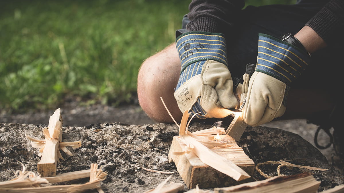Closeup of gloved hands lighting a campfire