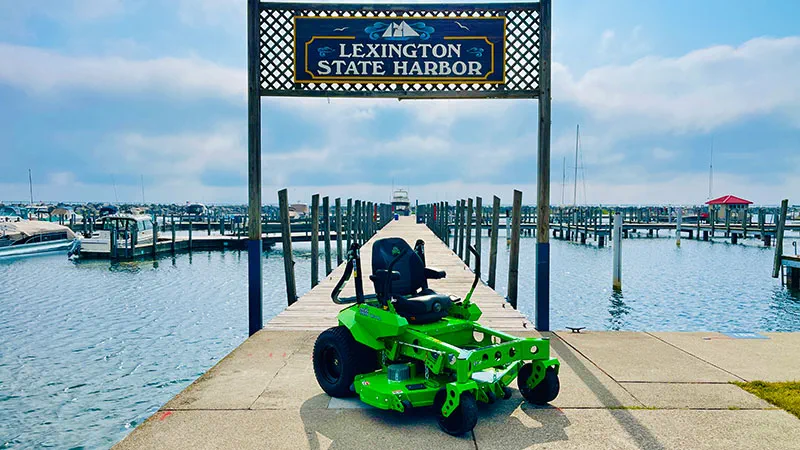 a green electric maintenance machine sits on a pier with a sign for Lexington State Harbor in the background 