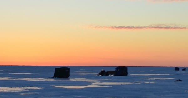 A few lone ice fishing shanties dot the ice at sunrise on Saginaw Bay