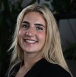 A young woman with straight, blond hair and light eyes grins at the camera.