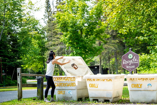 camper putting items in recycling bins in state park