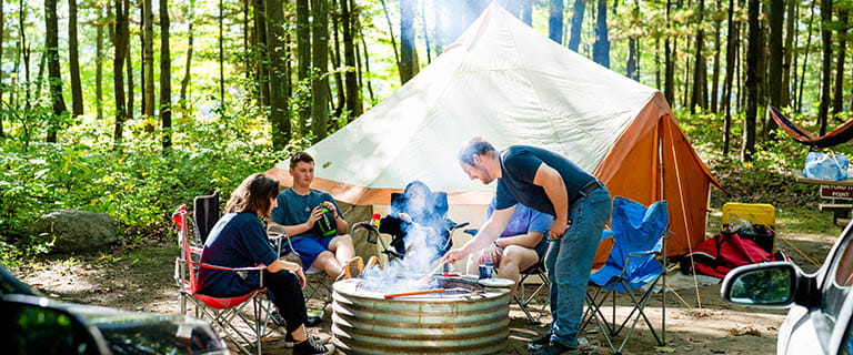 family sitting around campfire with tent in background