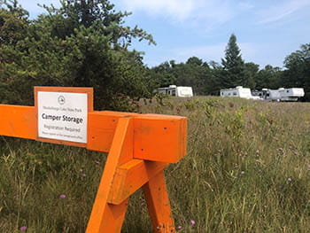 campers parked in field with camper storage signage 