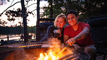 couple sitting at campfire at dusk