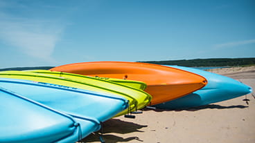 Colorful kayaks piled up on a beach