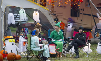 costumed campers sitting in front of decorated camper