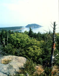 A view of the lake from atop a tall, rocky outcropping with verdant trees below.