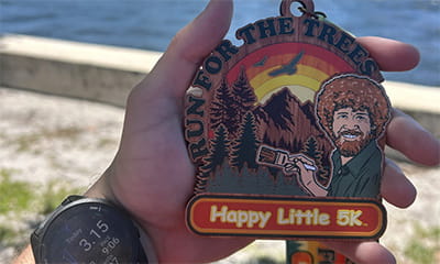 hand holding Happy Little Trees medal