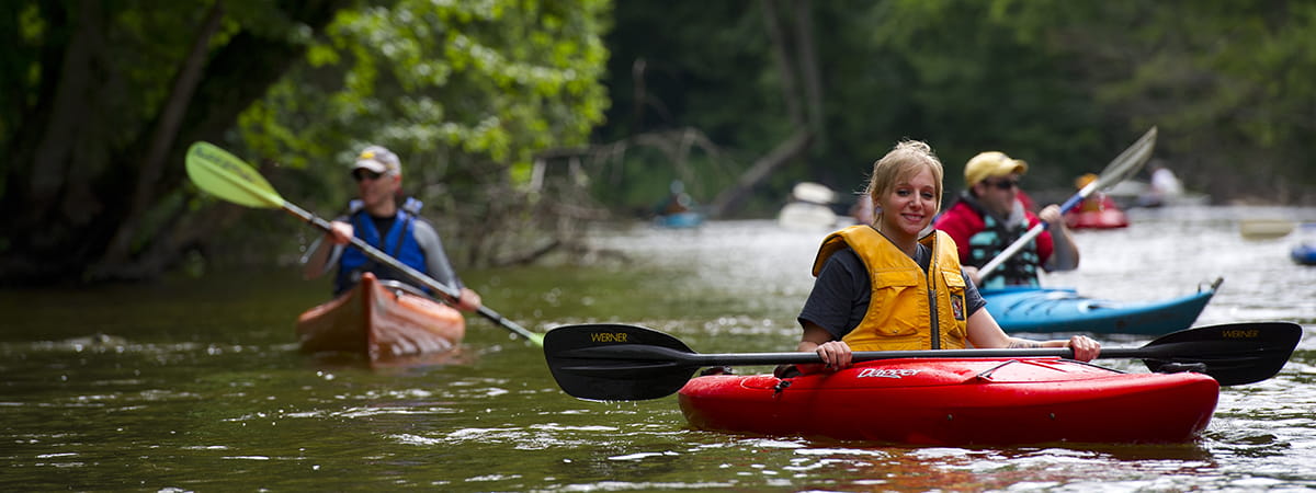 woman paddling in river with other paddlers in background
