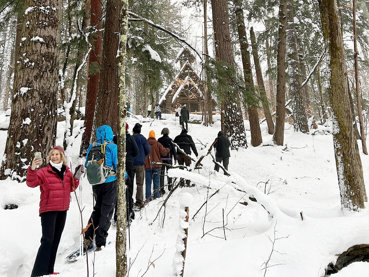 People hiking along snowy trail with someone taking a selfie