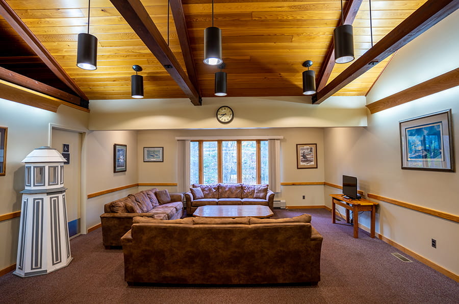 three leather couches, lighthouse decoration, small TV and wood-beam ceilings