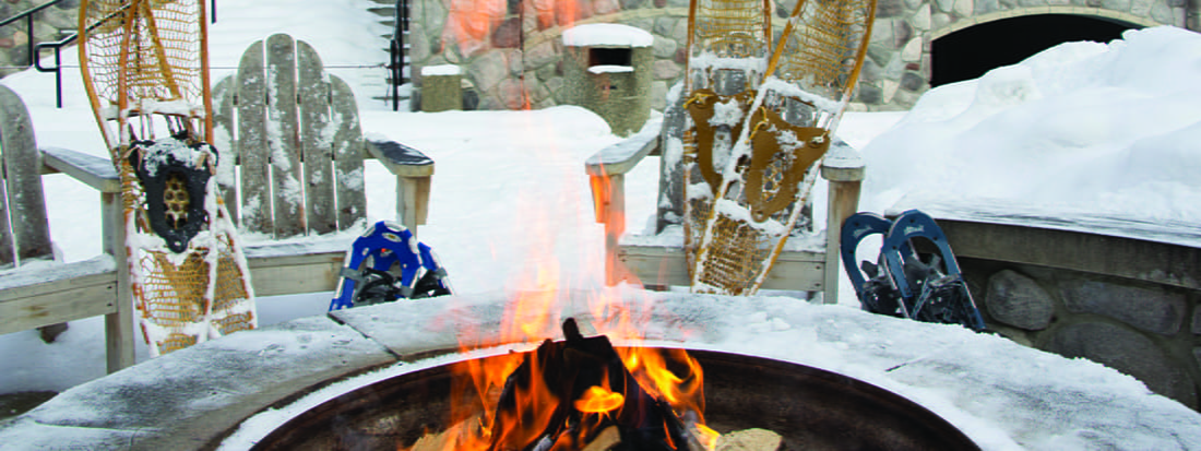 campfire with snow, chairs and snowshoes