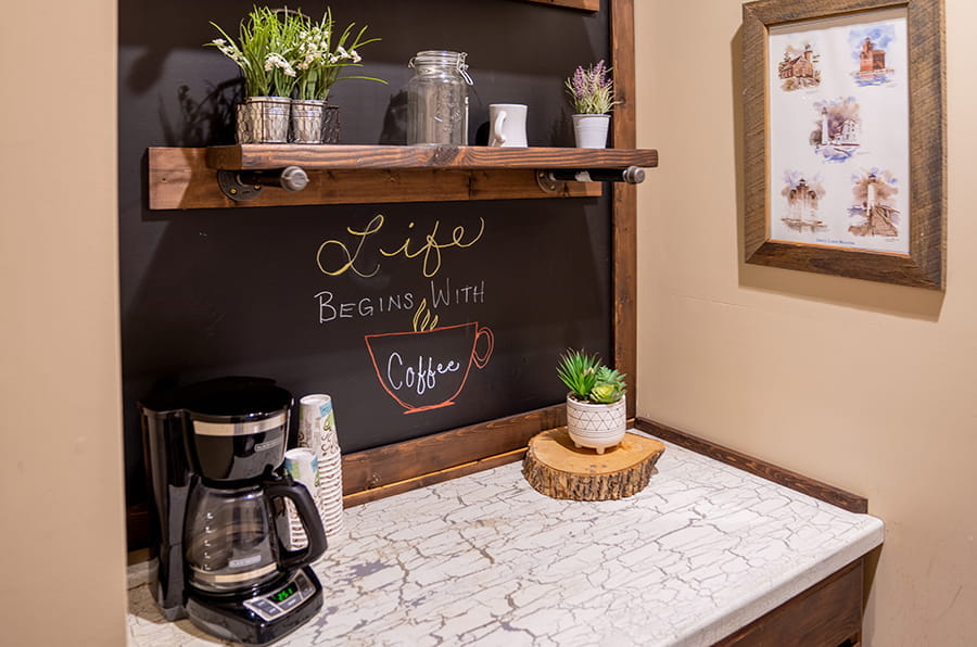 coffee station with coffee pot, mugs, chalkboard wall