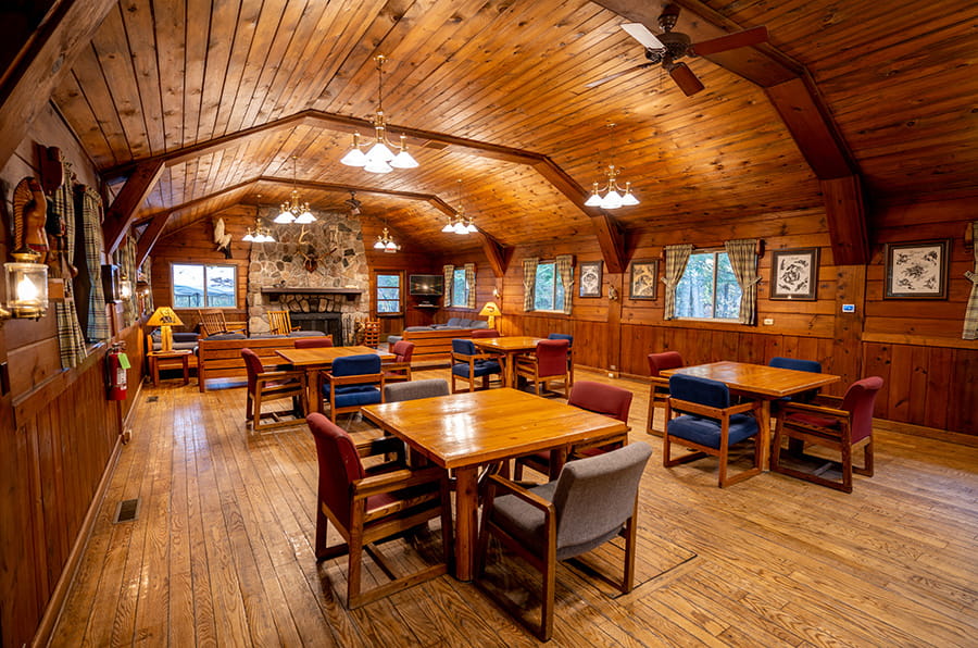 wooden tables in wood-paneled room with fireplace