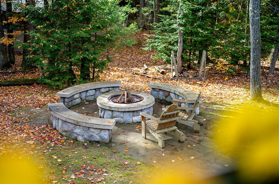 raised stone firepit with benches and a chair