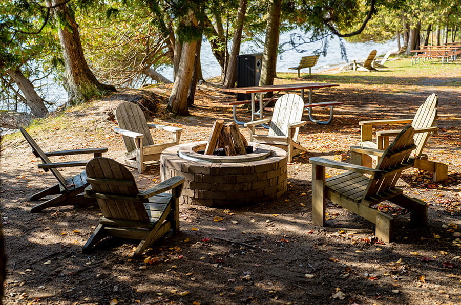 six chairs around firepit with lake in background