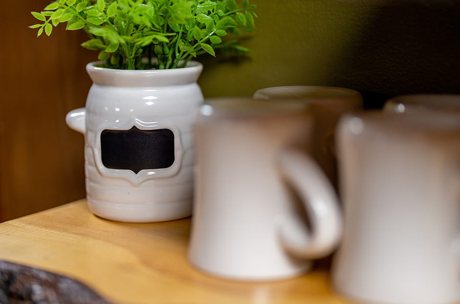 mugs with vase of flowers on wooden surface