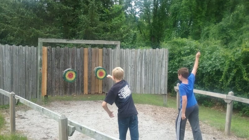 Two young men using Pontiac Lake Shooting Range axe and knife range