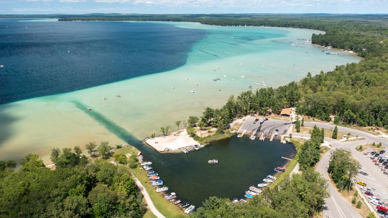 A birds eye view of Higgins lake with boats in the water and parked at launch site and campground in foreground 