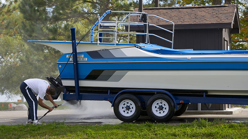 A boater sprays down the underside of his boat to prevent moving invasive species
