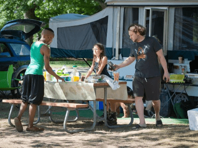 A family hangs out at a state park campsite with their RV in the background