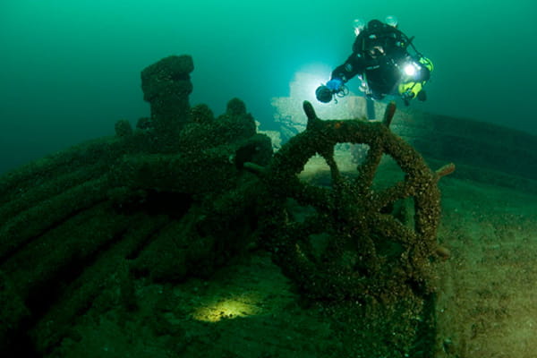 a diver exploring the steering wheel of a shipwreck