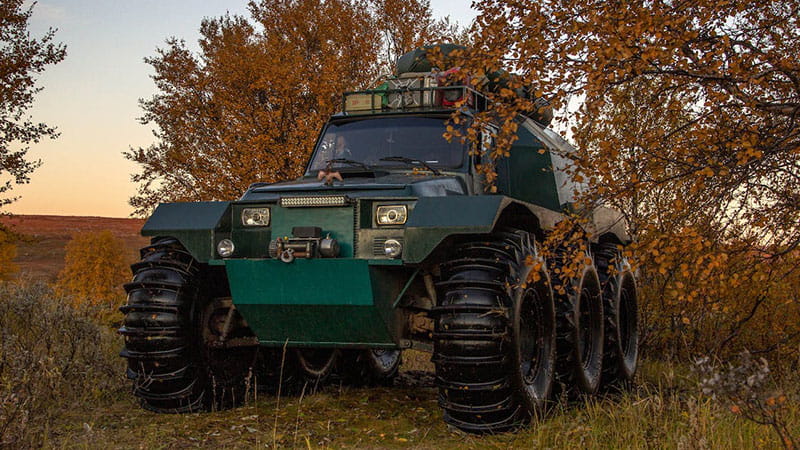 A six-wheeled Argo ORV in foreground with trees in background