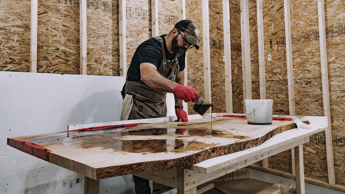 A woodworker stains a slice of wood