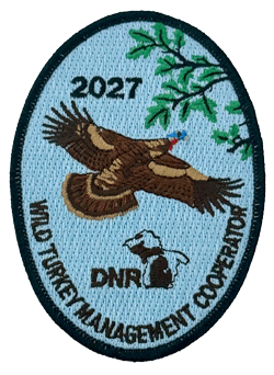 The 2027 Wild Turkey Management Cooperator patch: an oval embroidered patch showing a wild turkey in flight beneath an oak branch, with the DNR logo and the year 2027.