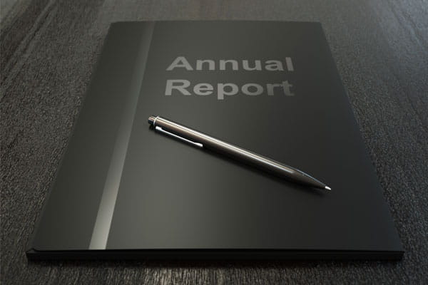 A black folder labeled annual report with a pen placed on the folder. 