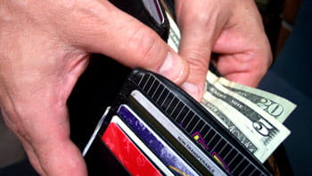 Image of a wallet  with a hand pulling out a 20, 5, and 1 dollar bill. 