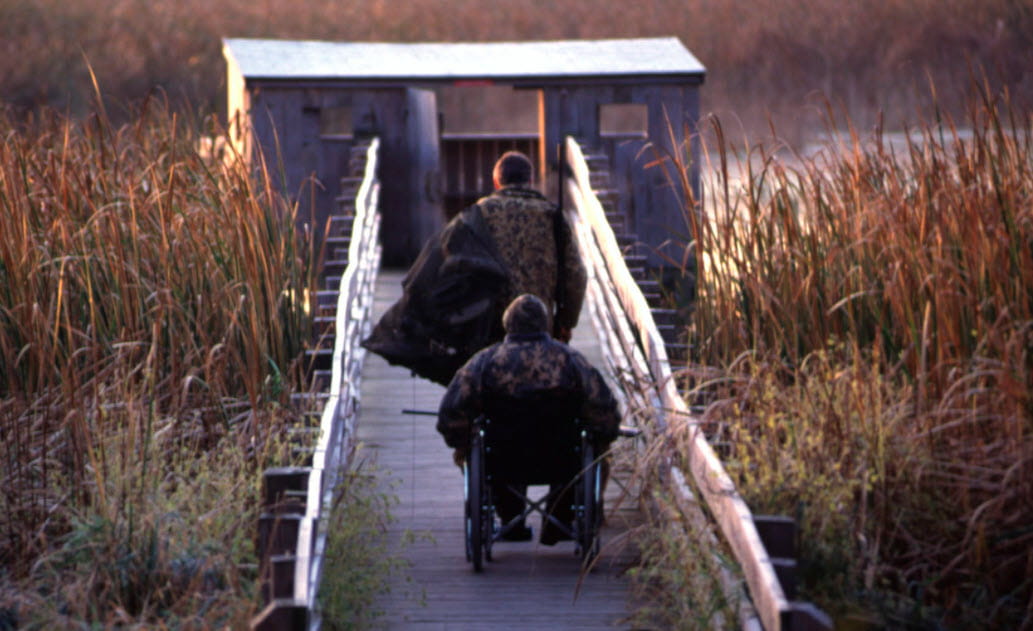 Two hunters on a wooden walkway