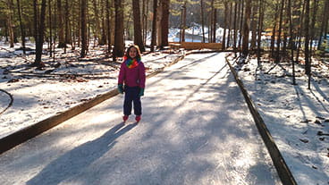 A child ice skates on a trail through the woods at Muskegon Luge Adventure Sports Park