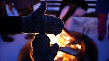 A pair of mittens held up in front of a campfire make the shape of Michigan's upper and lower peninsulas