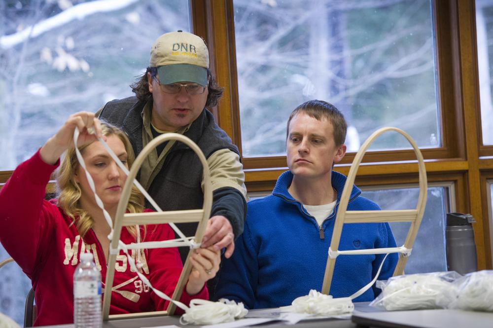 A park interpreter teaches a class on snowshoe making