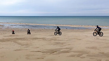 A group of people riding fat tire bikes at Silver Lake State Park sand dunes in the winter