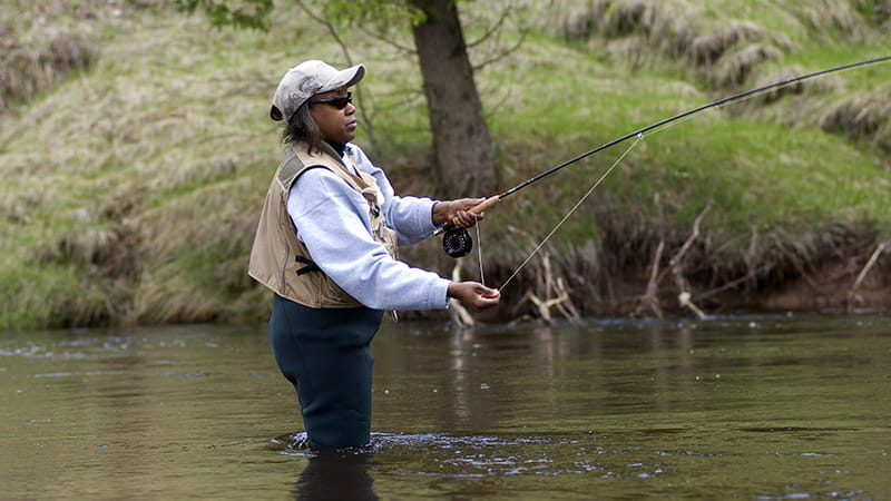 female angler standing in river fishing