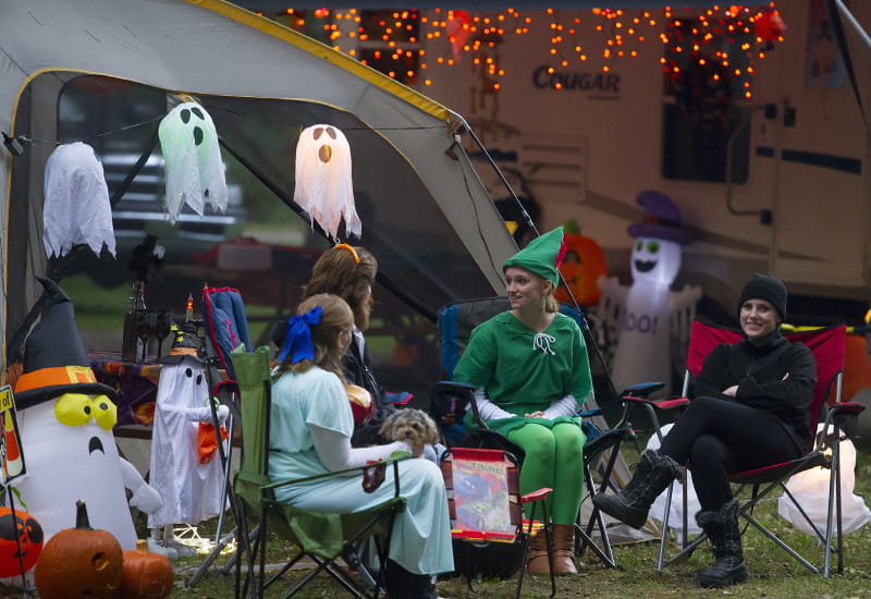 costumed campers sitting in Halloween-decorated campsite