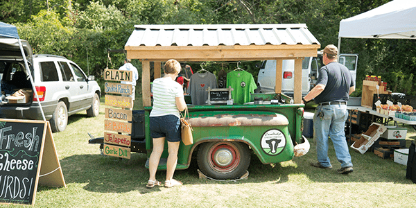 Two people visiting a booth at the farmers market.