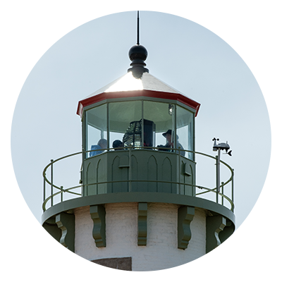 A group of people in the lantern room of the tower of Tawas Point Lighthouse.