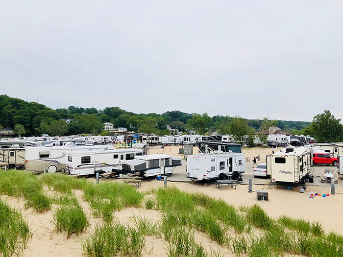 RVs and campers parked in campground with sand and dune grass photo by 