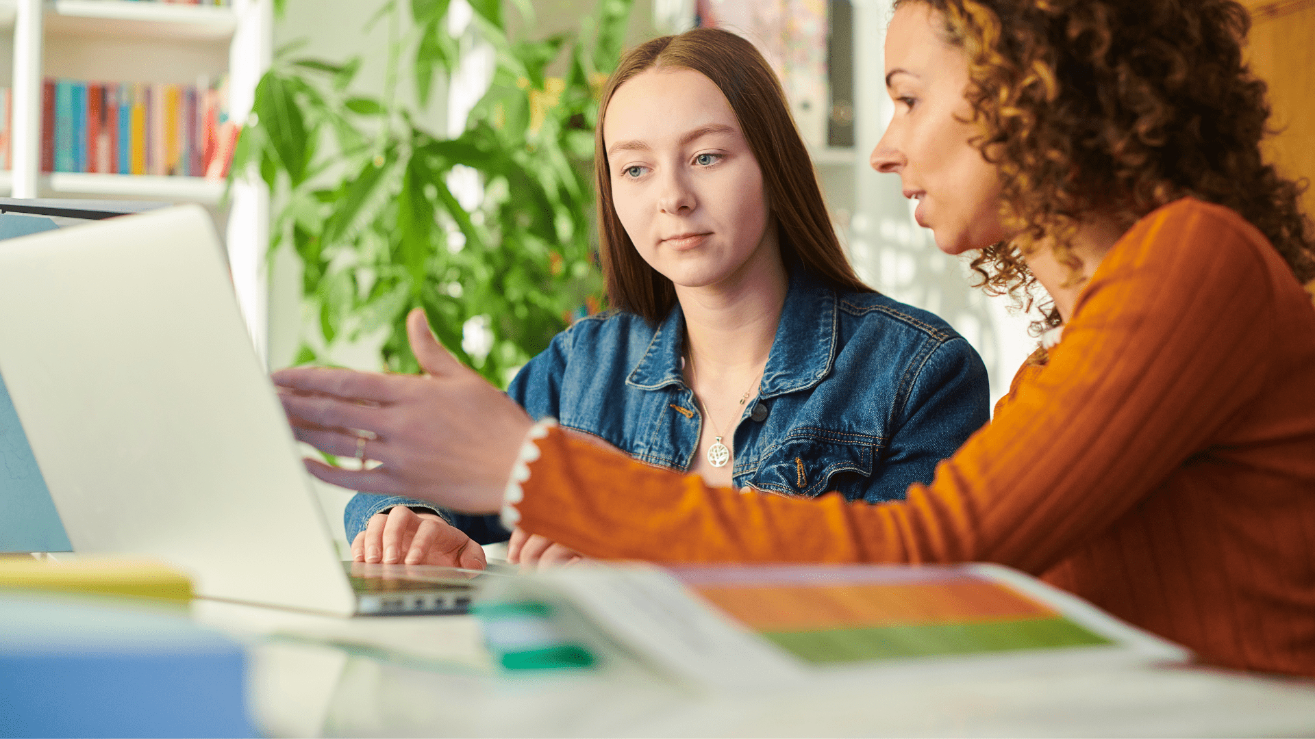 Image of two women sitting down at a table looking at a computer screen.